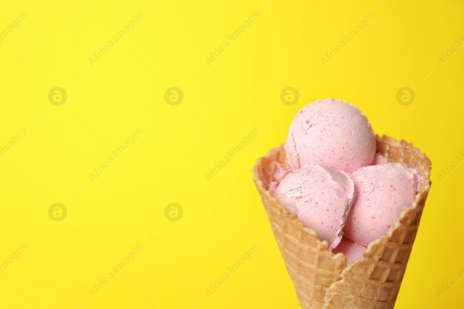 Photo of Delicious ice cream in waffle cone on color background, space for text