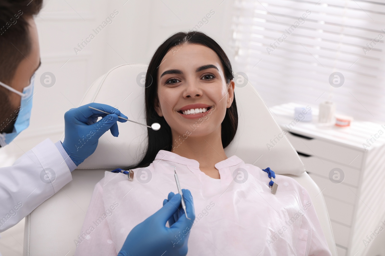 Photo of Dentist examining young woman's teeth in modern clinic