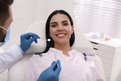 Dentist examining young woman's teeth in modern clinic