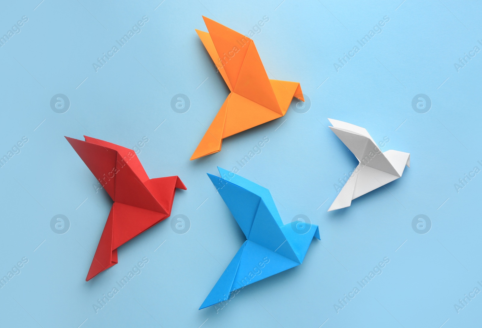 Photo of Origami art. Colorful handmade paper birds on light blue background, flat lay