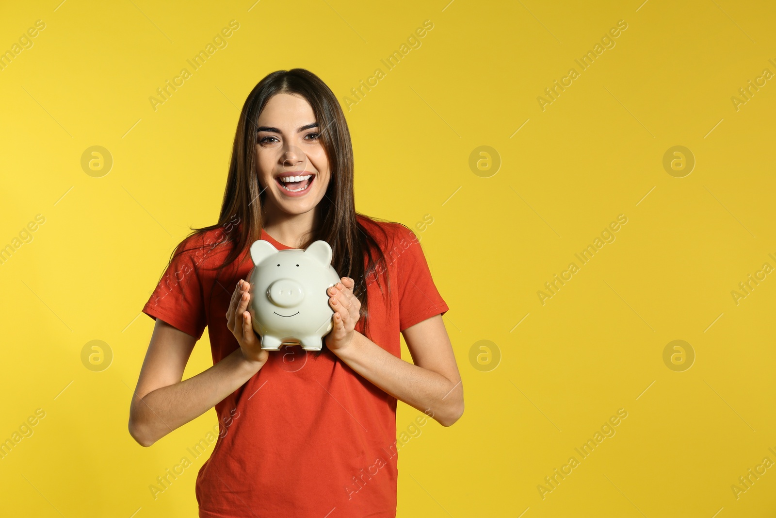 Photo of Young woman with piggy bank on color background, space for text. Money saving