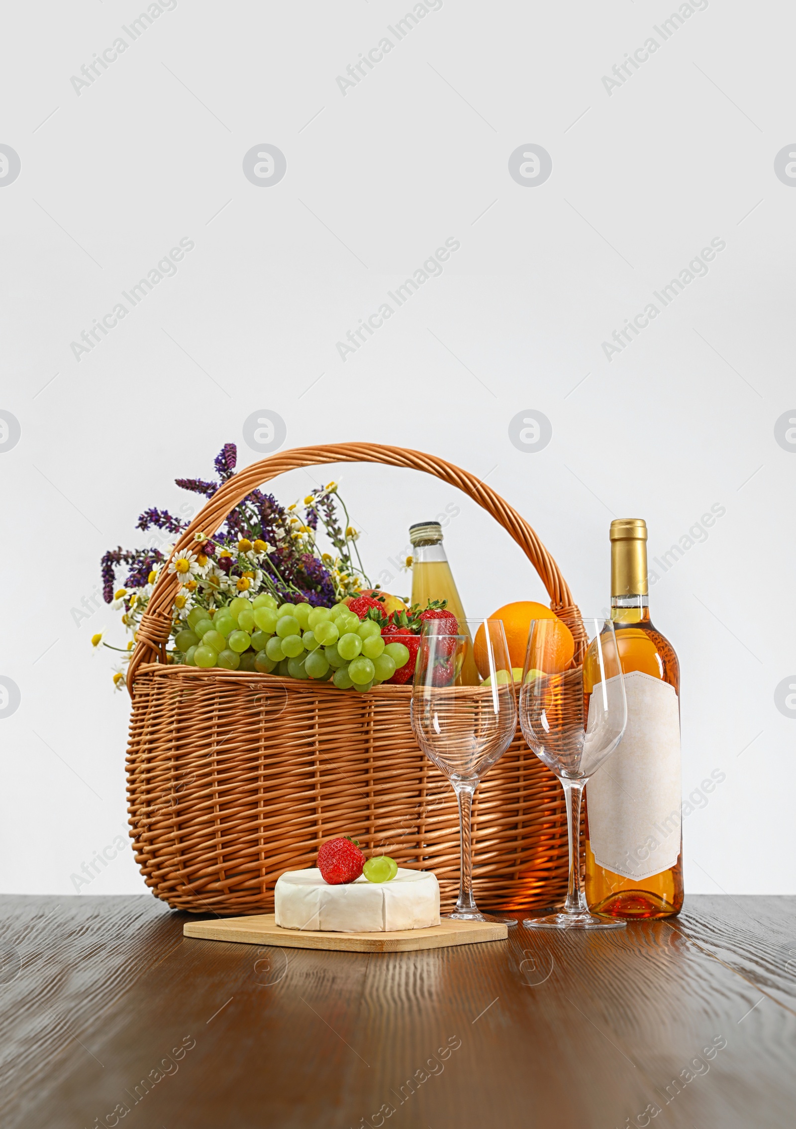 Photo of Picnic basket with wine and products on wooden table against white background