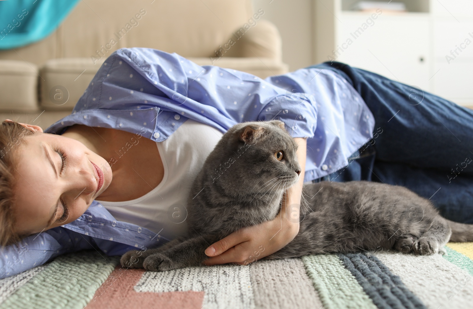 Photo of Young woman with her cute pet cat on floor at home