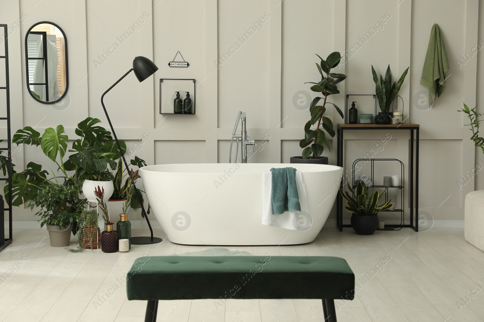 Photo of Stylish bathroom interior with modern tub and beautiful houseplants. Home design