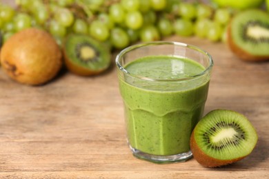 Photo of Glass of fresh green smoothie and ingredients on wooden table, space for text