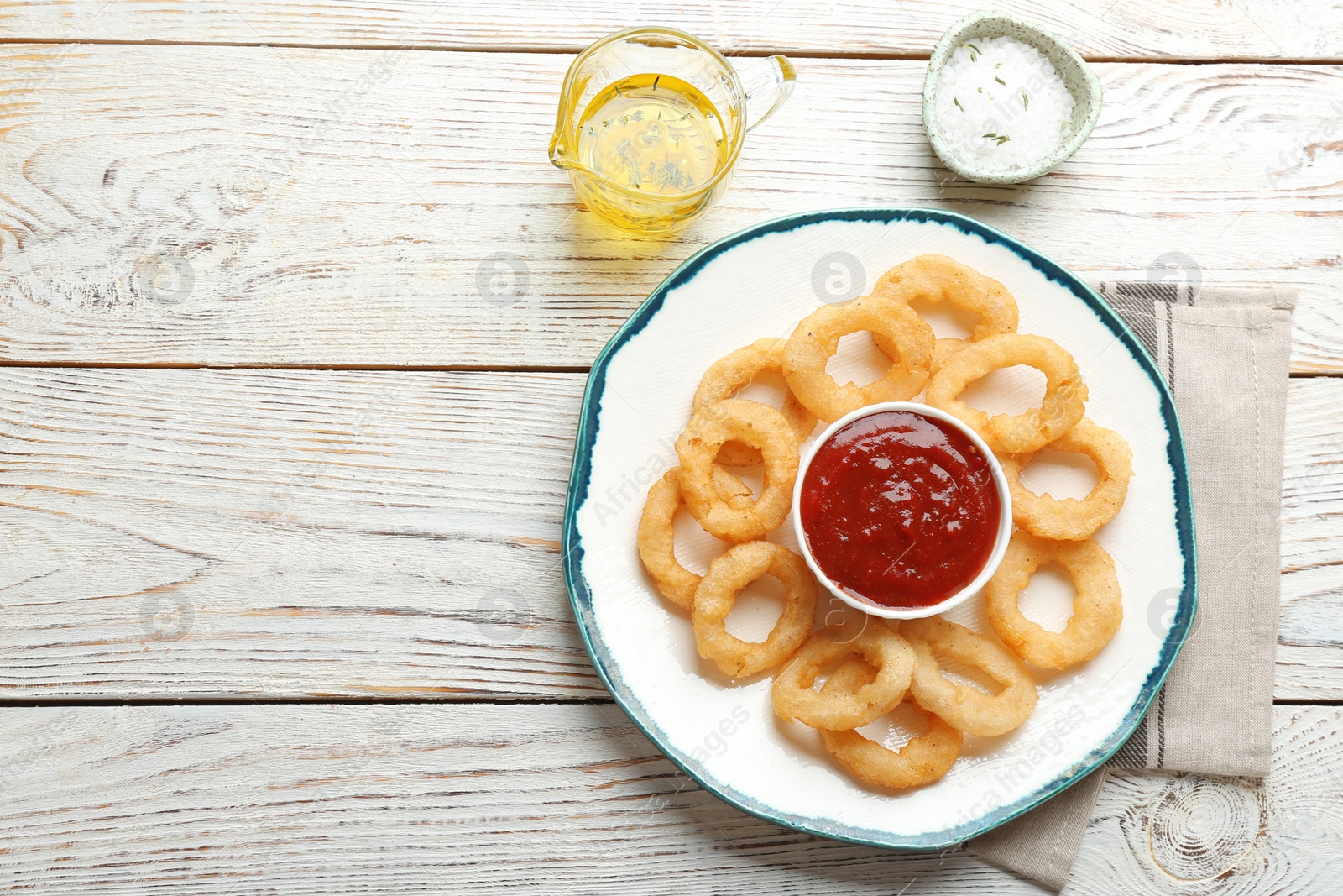 Photo of Plate with fried onion rings and sauce served on table, top view