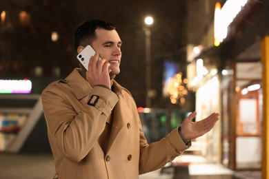 Photo of Man talking by smartphone on night city street