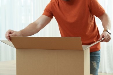 Photo of Man opening parcel indoors, closeup. Internet shopping