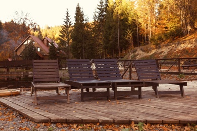Photo of Resort with wooden sunbeds near forest on sunny autumn day