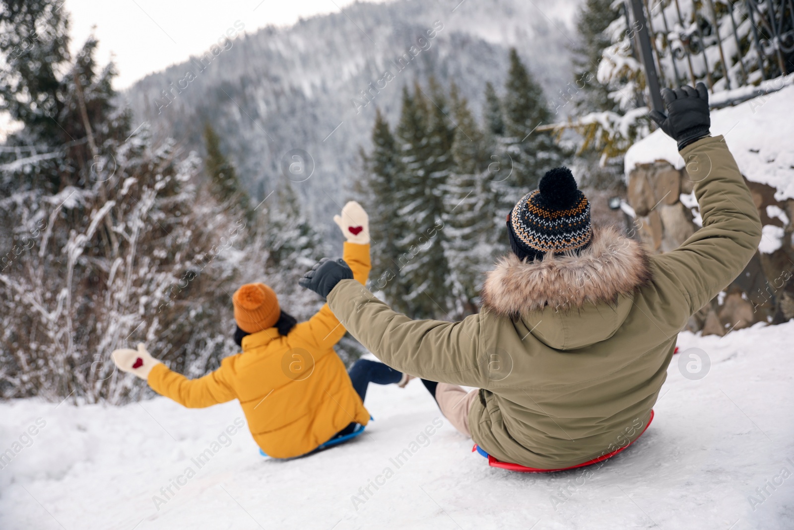 Photo of Couple having fun and sledding on snow. Winter vacation