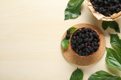 Wicker basket of delicious ripe black mulberries on white table, flat lay. Space for text