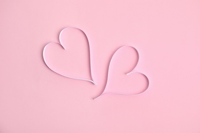 Photo of Hearts made of white ribbon on pink background, flat lay. Valentine's day celebration