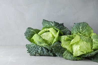Photo of Fresh green savoy cabbages on table against grey background