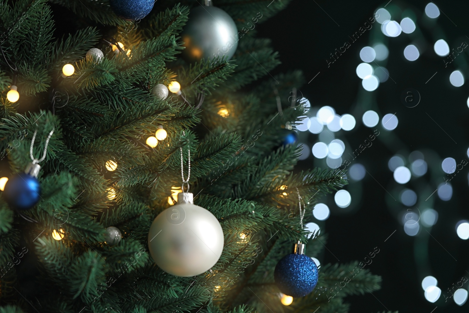 Photo of Beautiful Christmas tree with decor against blurred lights on background