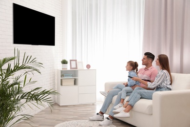 Happy family watching TV on sofa at home