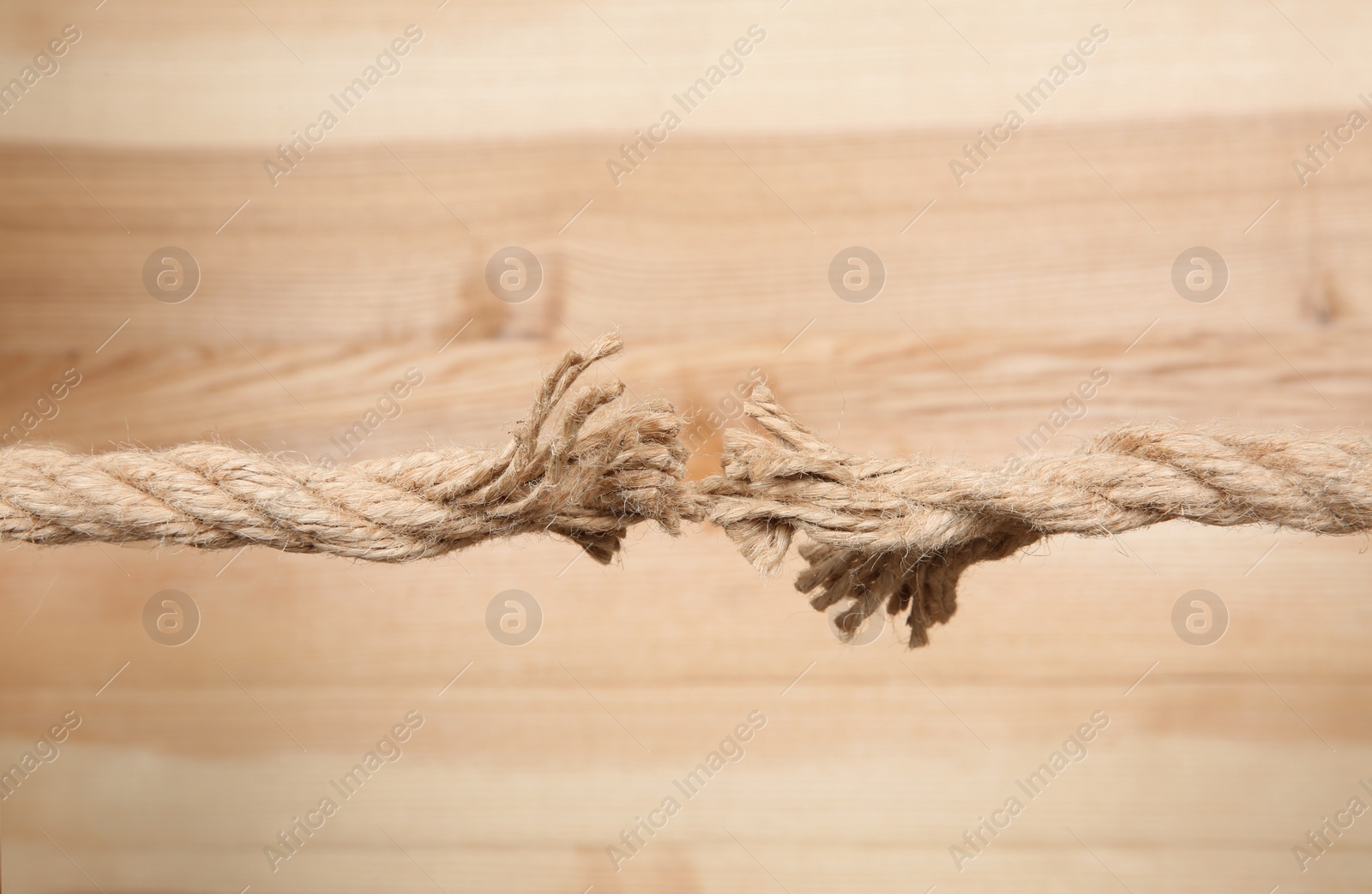 Photo of Frayed rope at breaking point on wooden background
