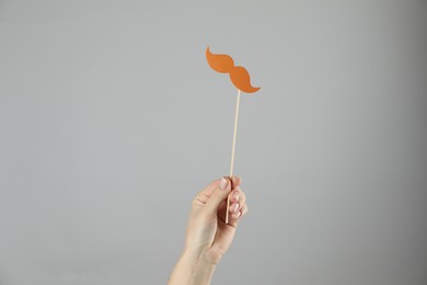 Photo of Woman with fake paper mustache on gray background, closeup