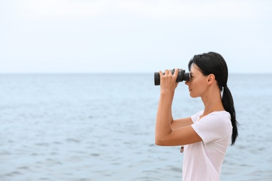 Beautiful female lifeguard with binocular near sea