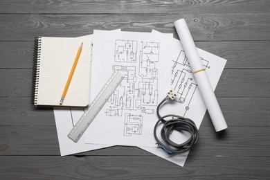 Wiring diagrams, wires and office stationery on grey wooden table, flat lay