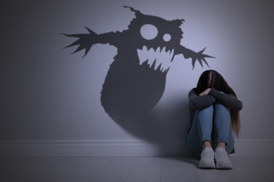 Image of Shadow of monster on wall and scared teenage girl in room