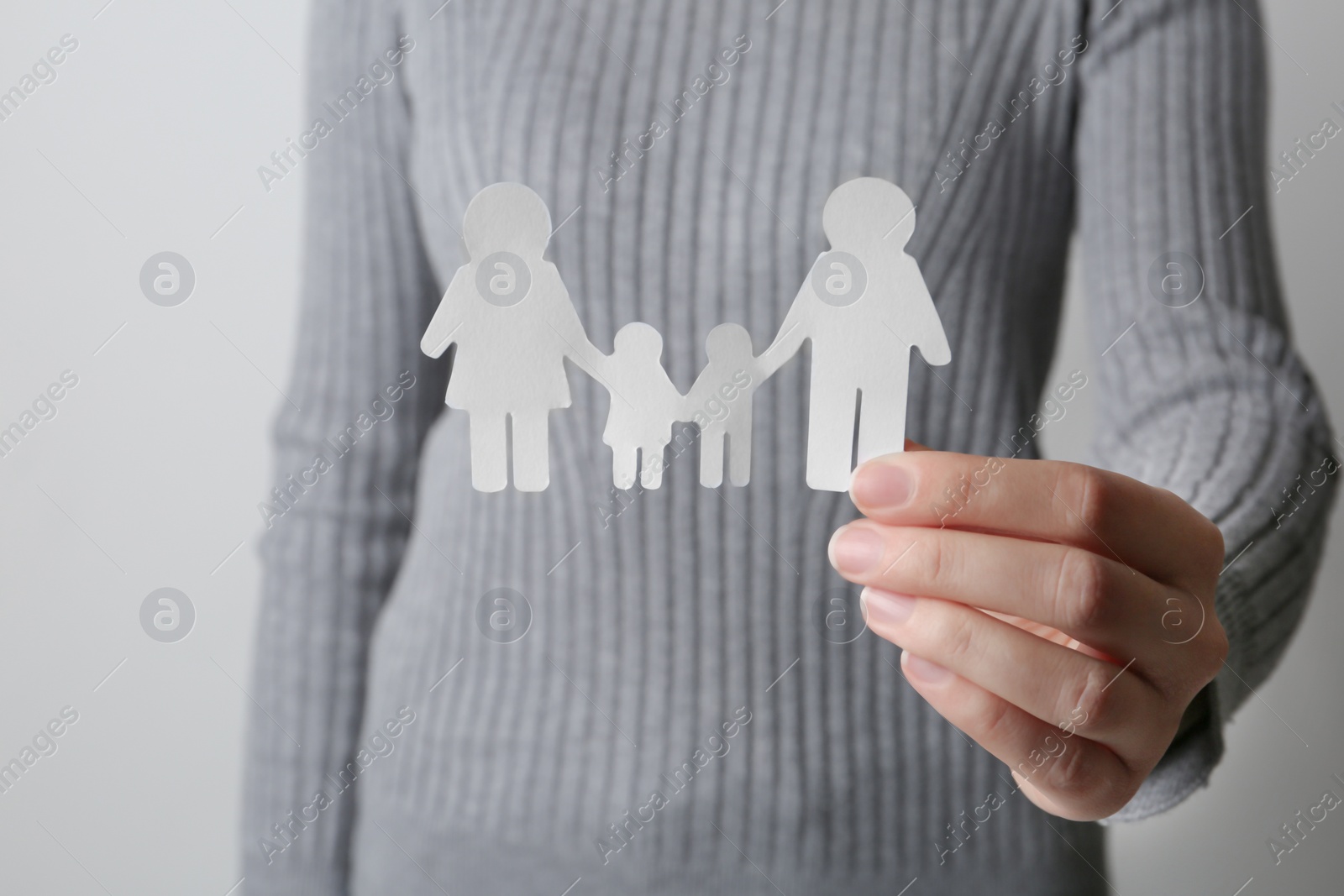 Photo of Woman holding paper silhouette of family on grey background, closeup. Life insurance concept