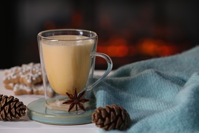 Photo of Tasty eggnog, anise star and cones on white wooden table, closeup