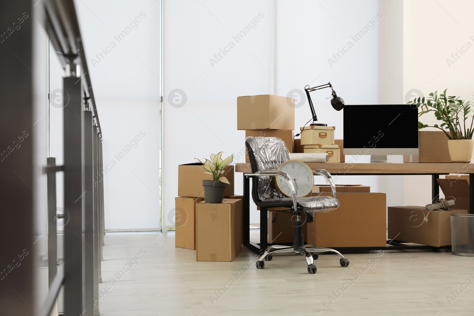 Photo of Cardboard boxes, computer and furniture in new office. Moving day