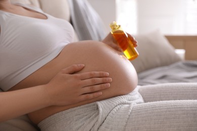 Photo of Young pregnant woman with cosmetic product indoors, closeup