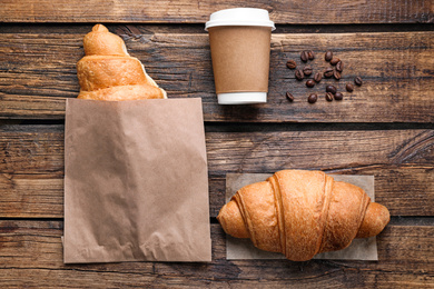 Tasty croissants and coffee on wooden table, flat lay