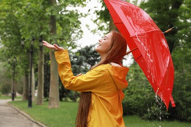 Photo of Young woman with umbrella walking under rain in park
