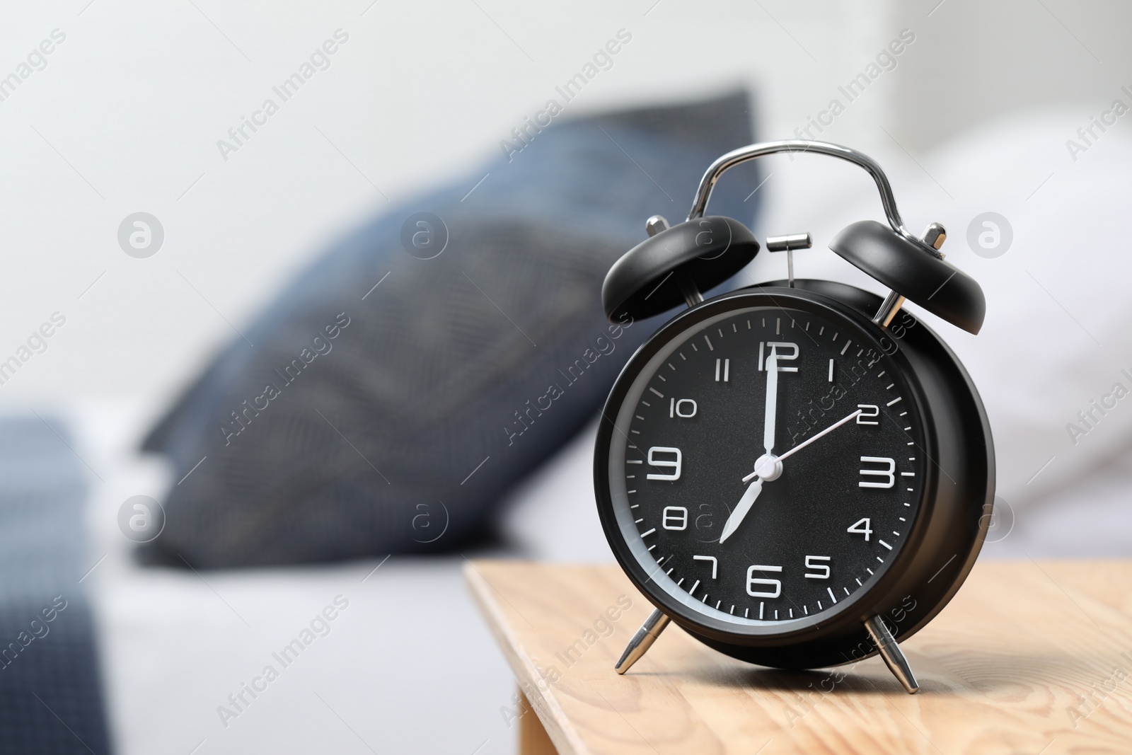 Photo of Black alarm clock on wooden nightstand in bedroom, space for text