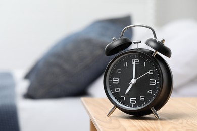 Photo of Black alarm clock on wooden nightstand in bedroom, space for text