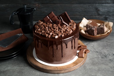 Photo of Freshly made delicious chocolate cake on grey table against black background