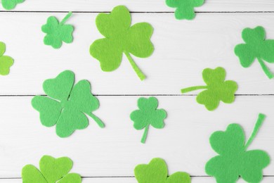 Photo of St. Patrick's day. Decorative green clover leaves on white wooden table, flat lay