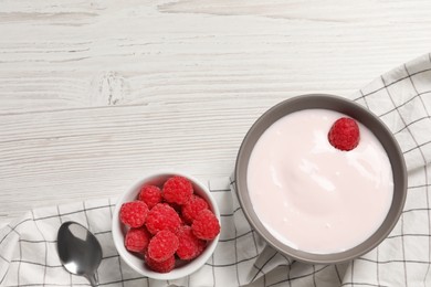 Photo of Bowl of tasty yogurt served with raspberries on white wooden table, flat lay. Space for text