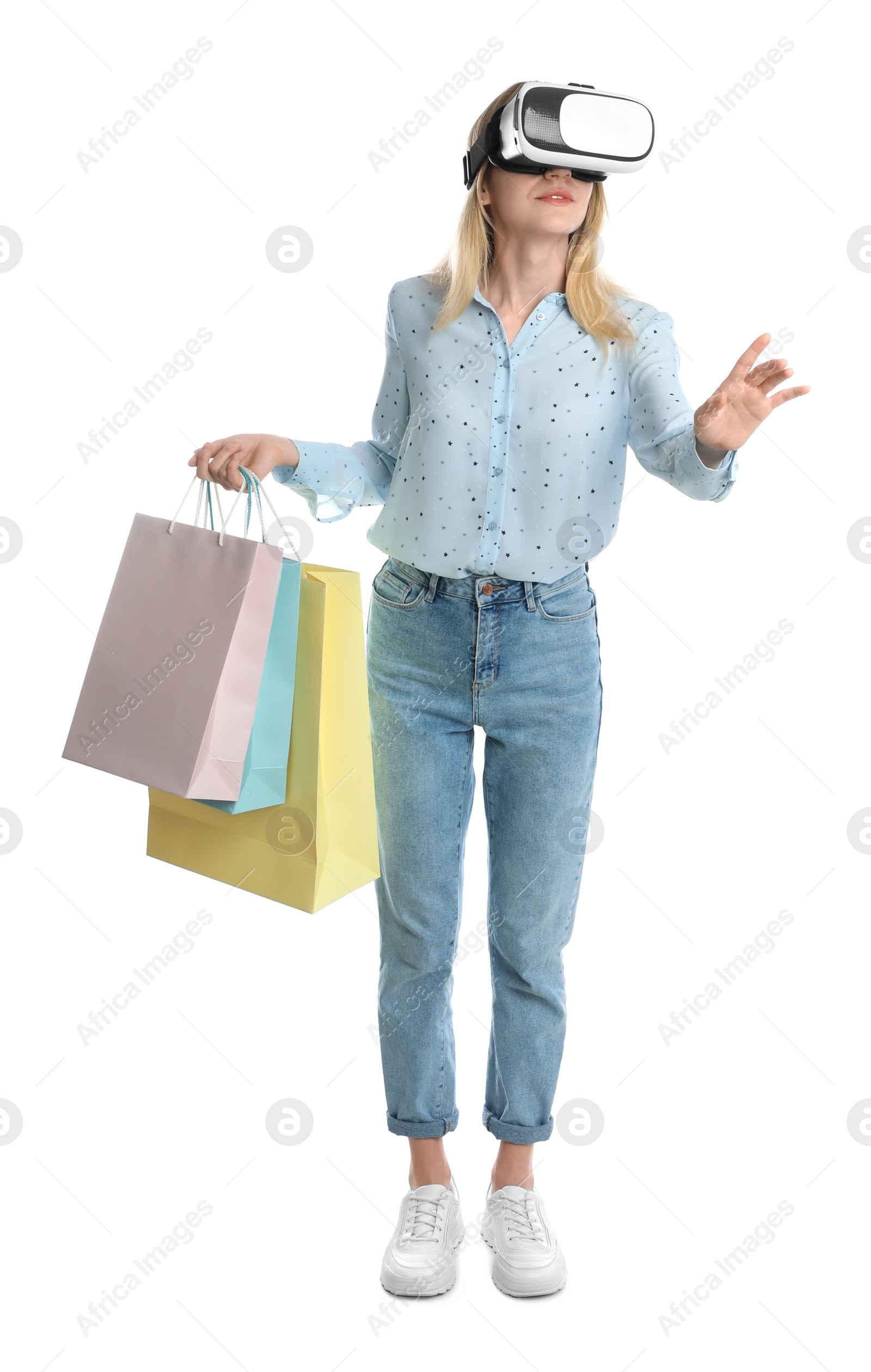 Photo of Young woman with shopping bags using virtual reality headset on white background