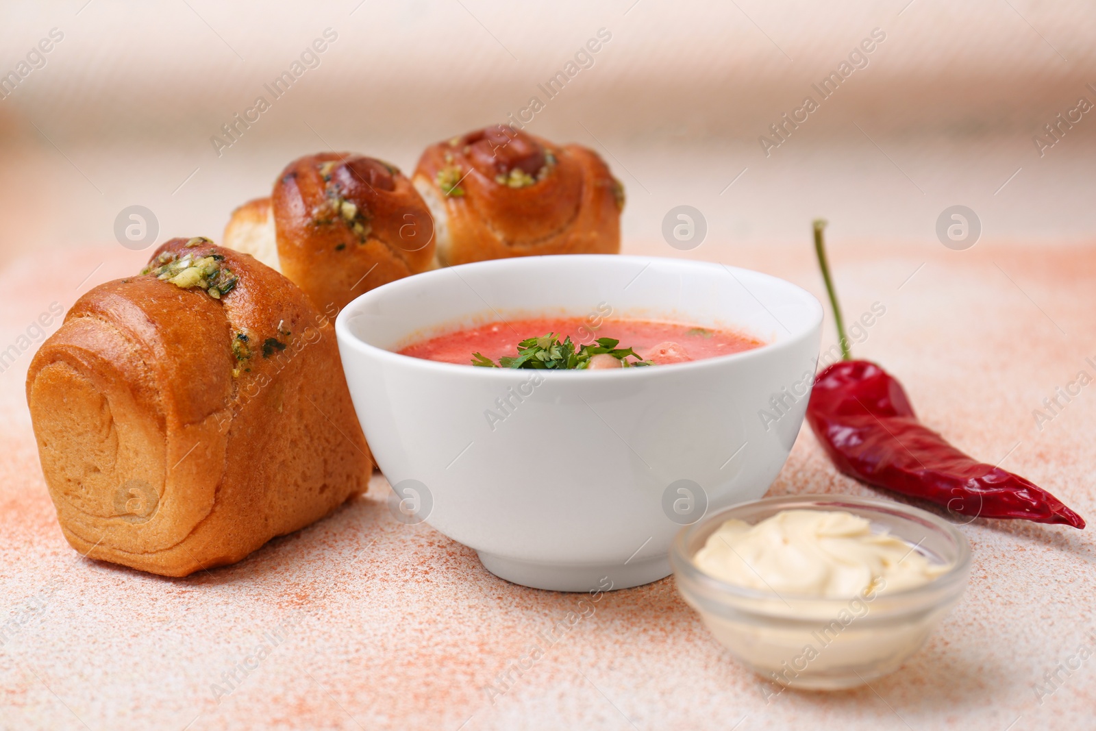 Photo of Delicious borsch served with pampushky on color textured table. Traditional Ukrainian cuisine