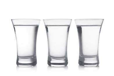 Cold vodka in shot glasses on white background