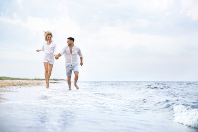 Photo of Happy couple running on beach, space for text. Romantic walk