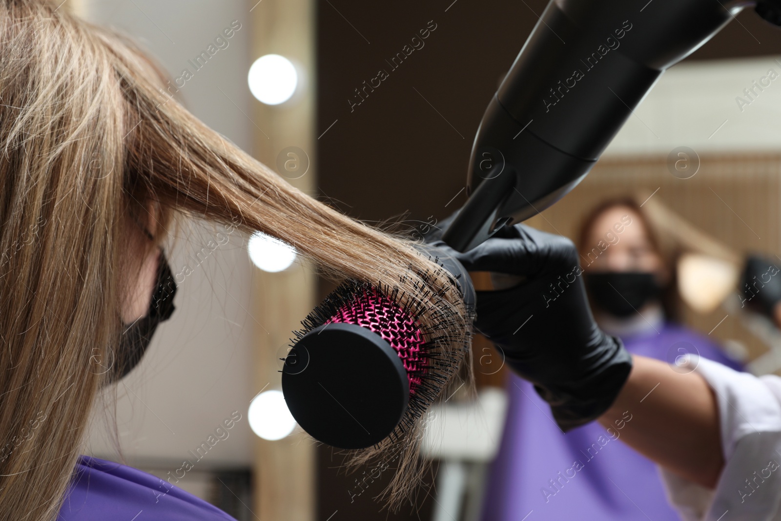 Photo of Professional stylist working with client in beauty salon, closeup. Hairdressing services during Coronavirus quarantine