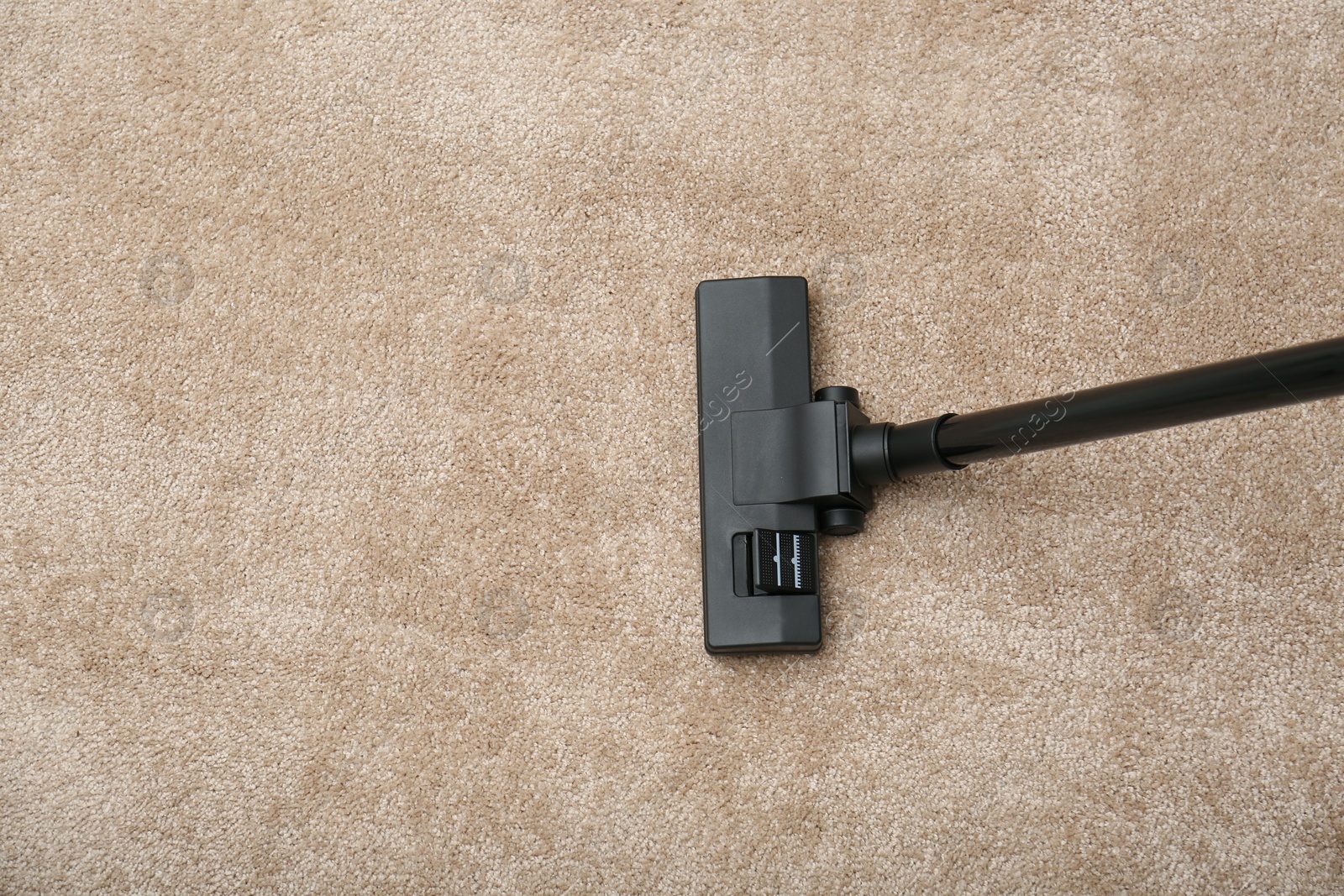 Photo of Removing dirt from carpet with modern vacuum cleaner indoors, top view. Space for text