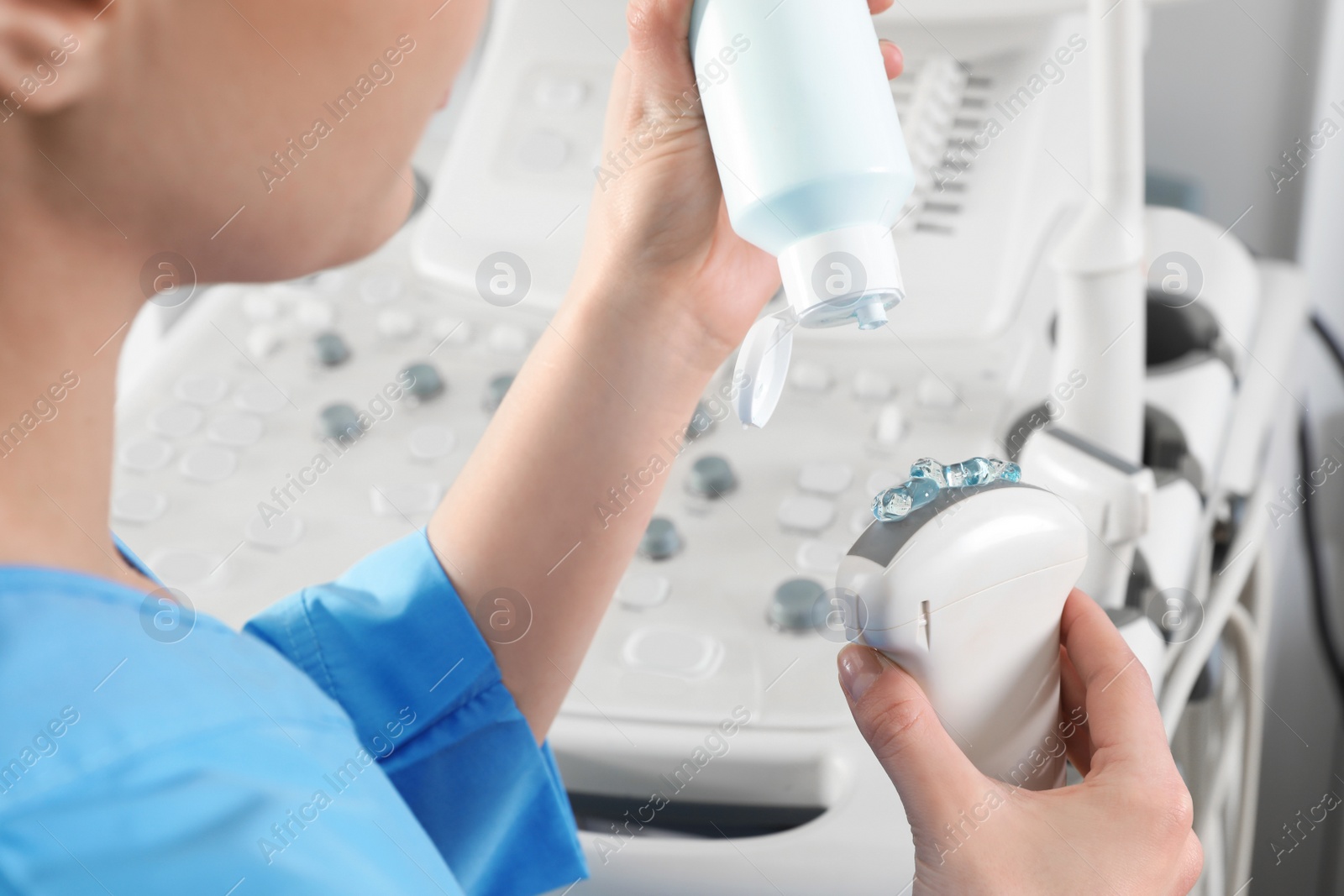 Photo of Sonographer covering ultrasound machine probe with gel in clinic, closeup