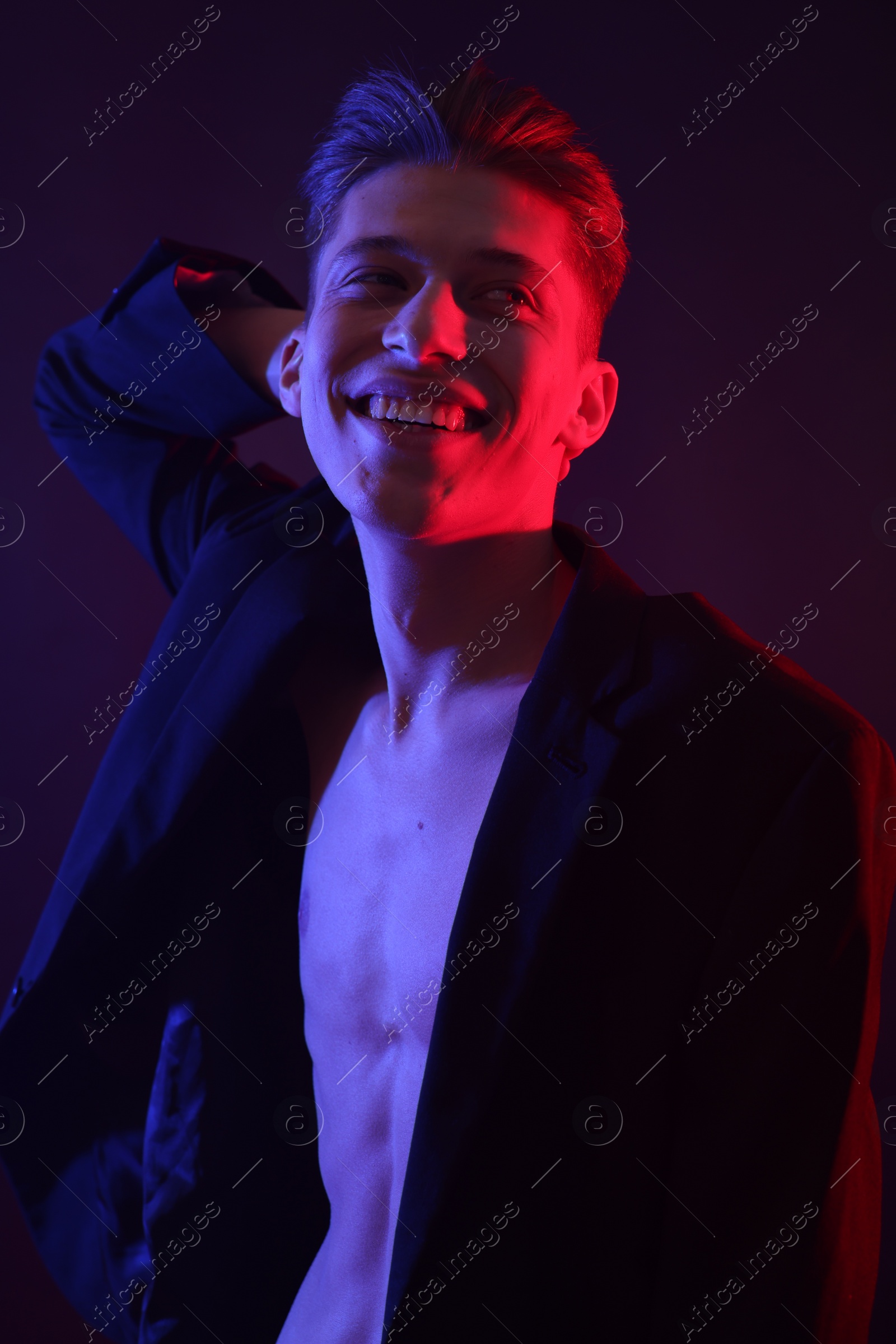 Photo of Sexy young man on dark background in neon lights