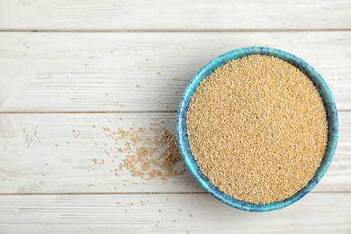 Bowl with white quinoa and space for text on wooden background, top view