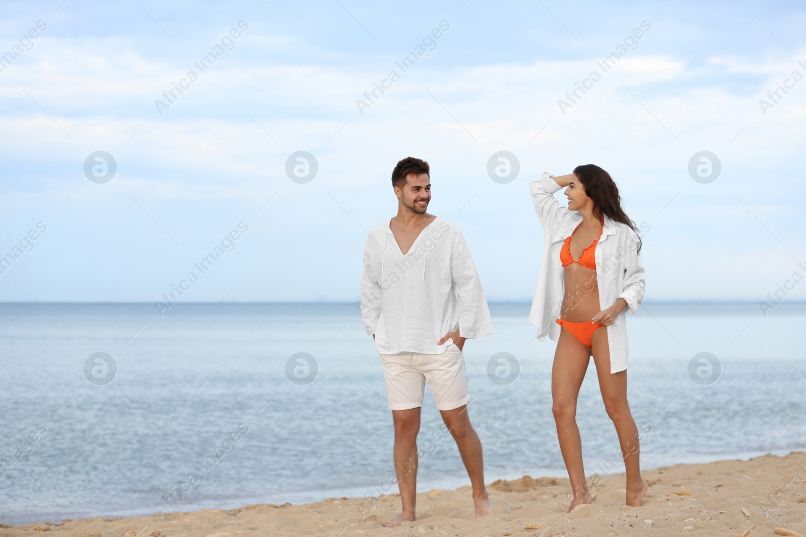 Photo of Happy young couple walking together on beach near sea