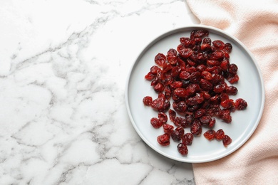 Photo of Plate with cranberries on marble table, top view with space for text. Dried fruit as healthy snack