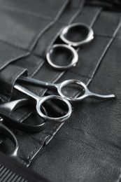 Photo of Hairdresser tools. Professional scissors and comb in leather organizer, closeup