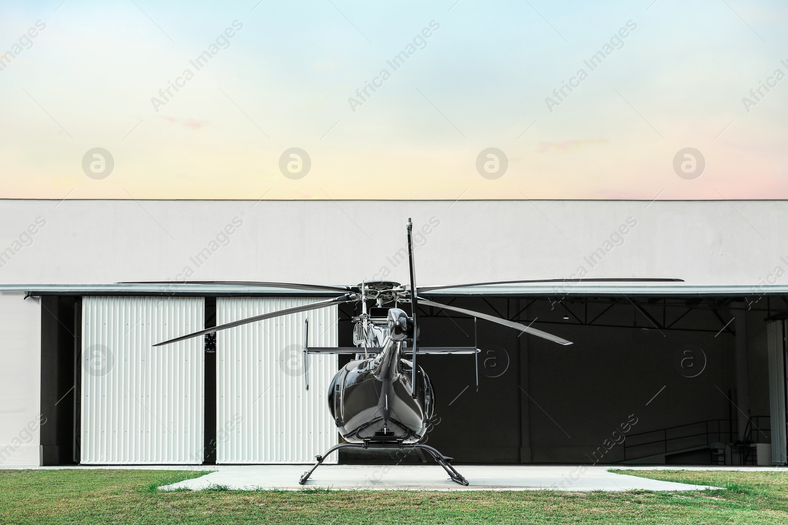 Photo of Beautiful helicopter on helipad in field near hangar