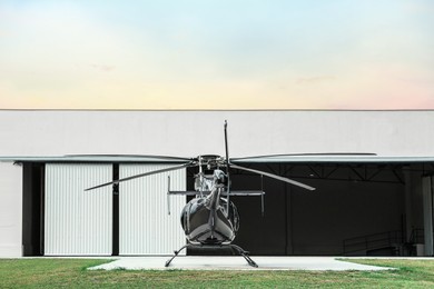 Photo of Beautiful helicopter on helipad in field near hangar