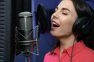 Photo of Young singer with microphone recording song in studio